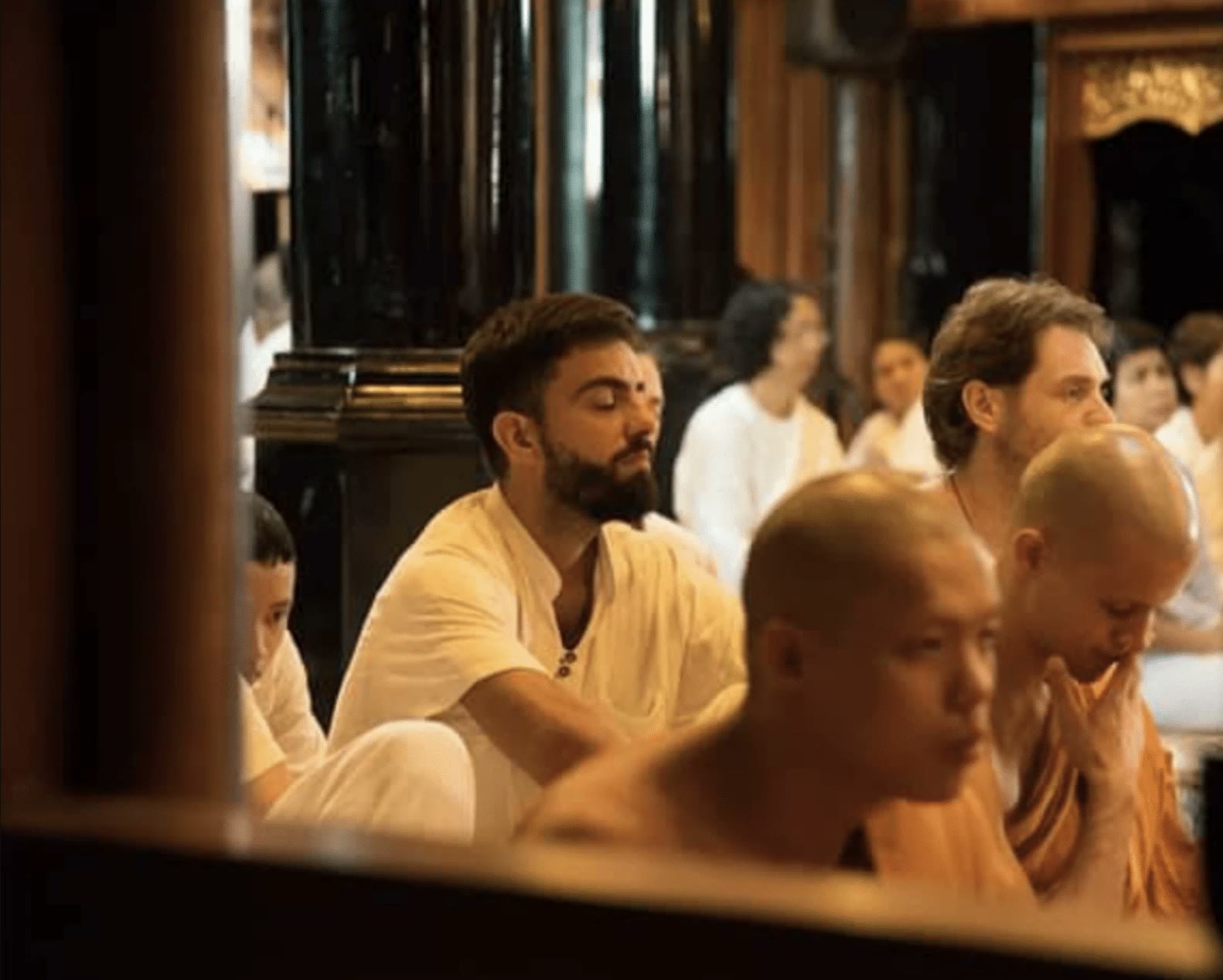 Diego meditando con los ojos cerrados junto a monjes budistas